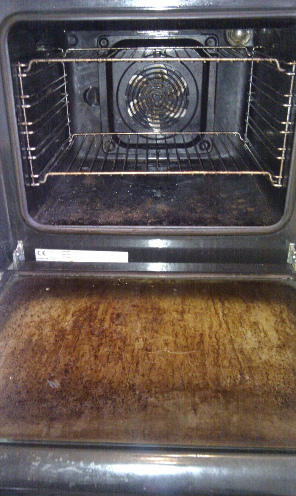 A fan oven before cleaning, with burnt-on grease on the door glass